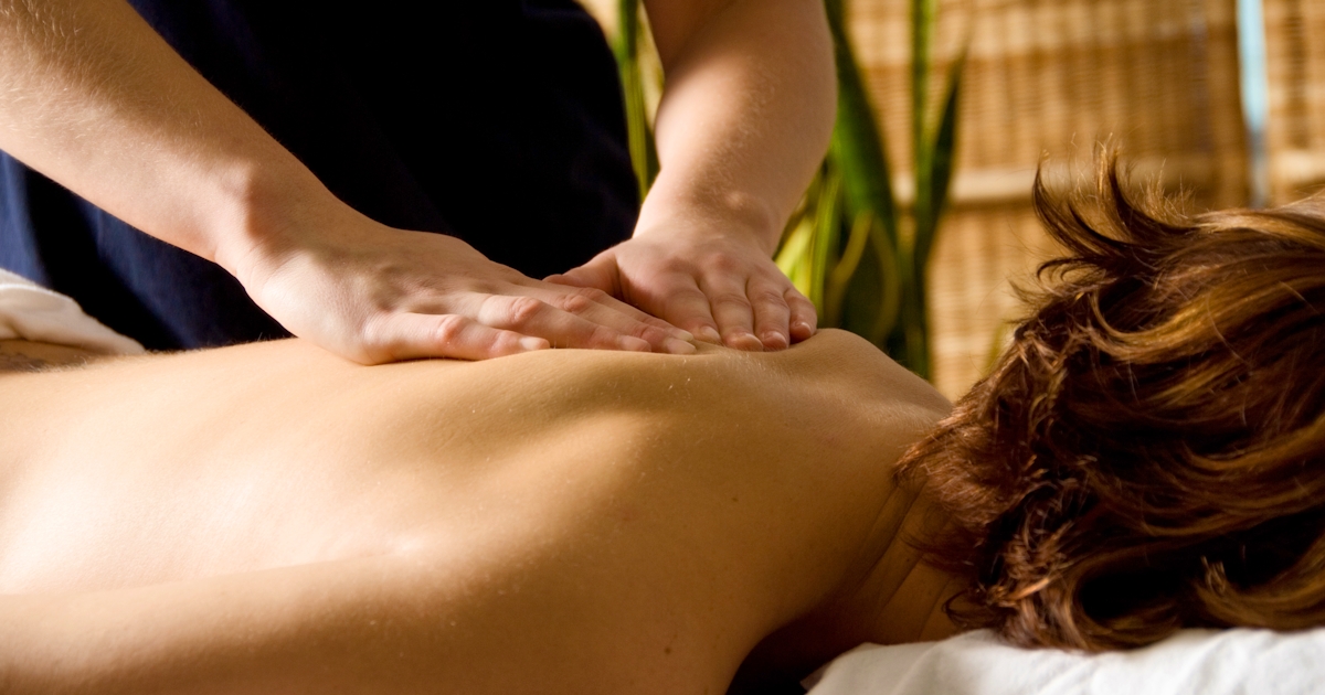 The image shows a person receiving a massage, with a focus on the back and the hands of the masseuse, set in a serene environment.