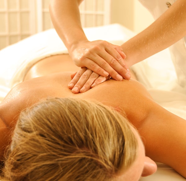 The image shows a person receiving a massage on a treatment table, with a calming setting and gentle hands providing the therapy.