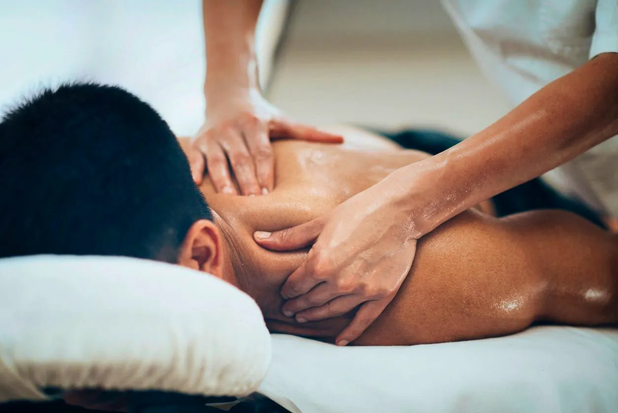 Massage therapist providing deep tissue massage on a man's shoulders and upper back to relieve muscle tightness at a clinic in Joondalup.jpeg