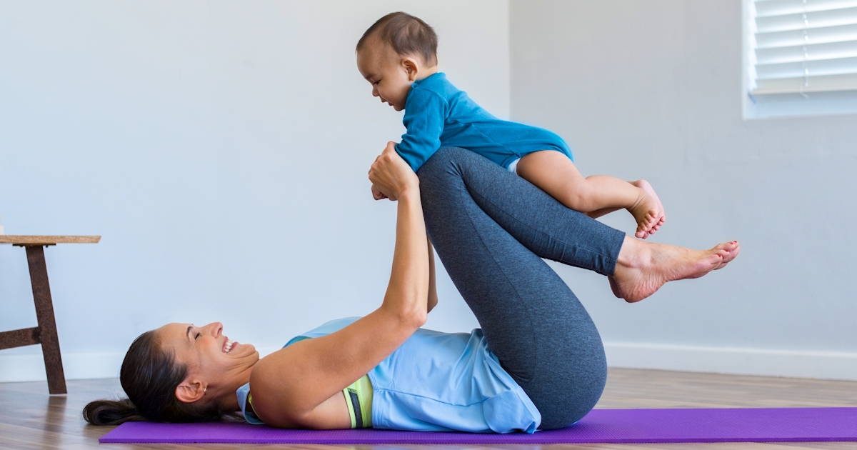 mother with baby on yoga mat in studio having fun
