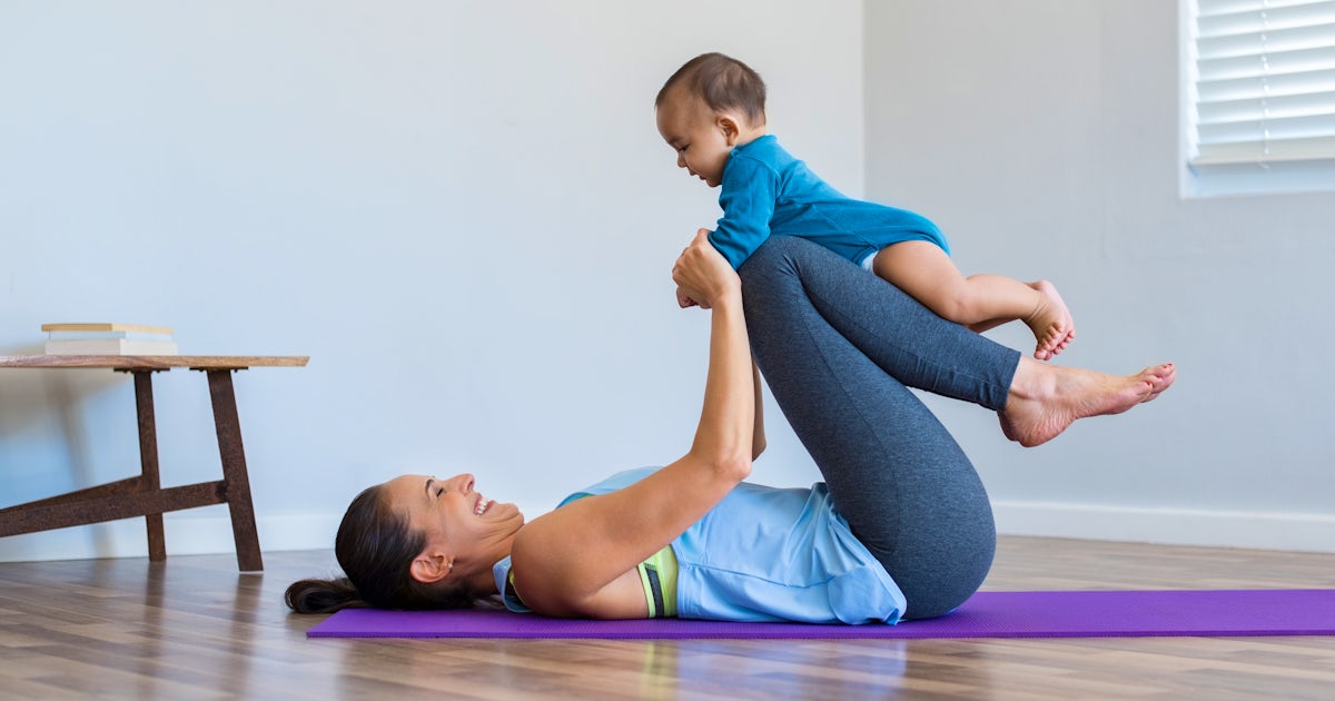 mother with baby on yoga mat in studio having fun