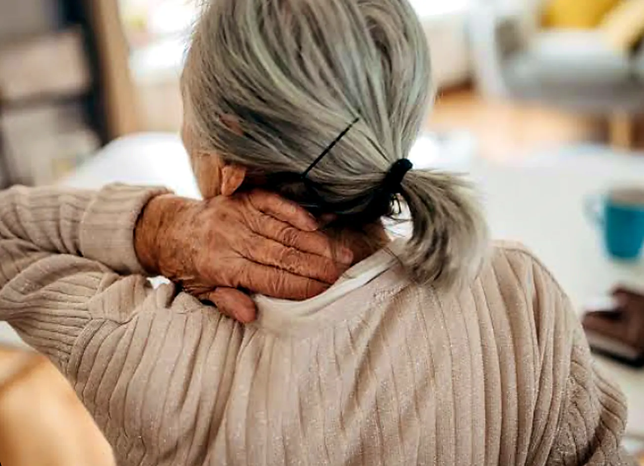 Older woman holding the back of her neck with cervical osteoarthritis pain and stiffness