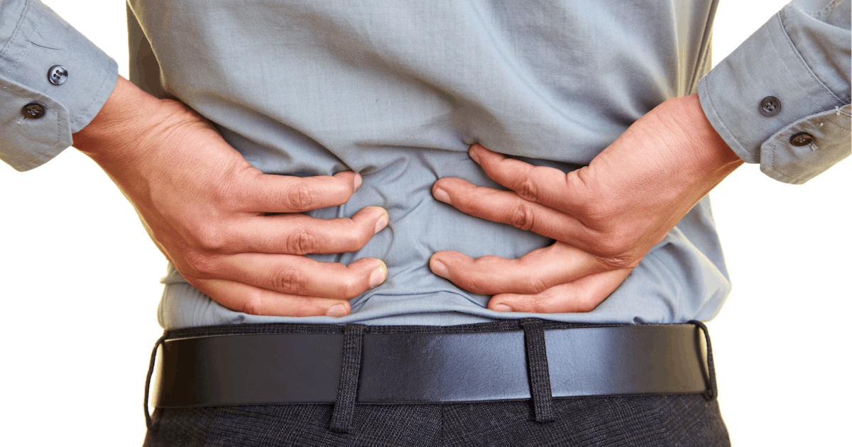 back of middle half of clothed white male with hands on low back pain