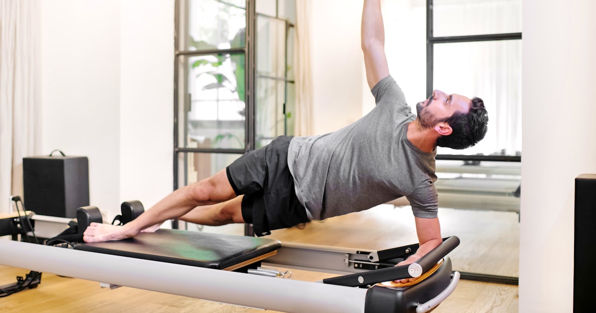 Fit man doing pilates side elbow plank exercises