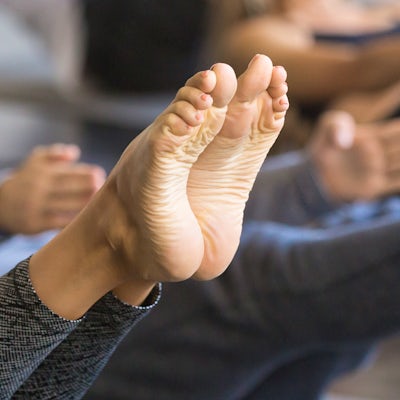Group of young sporty people in Paripurna Navasana