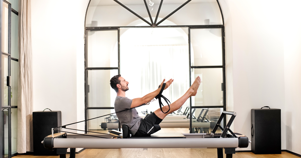 Man performing pilates teaser exercise in a gym