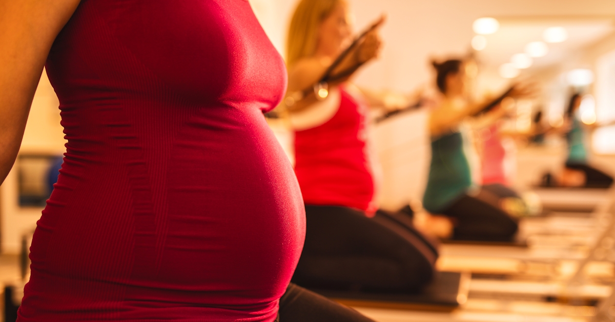 Unrecognizable pregnant woman practicing on Pilate