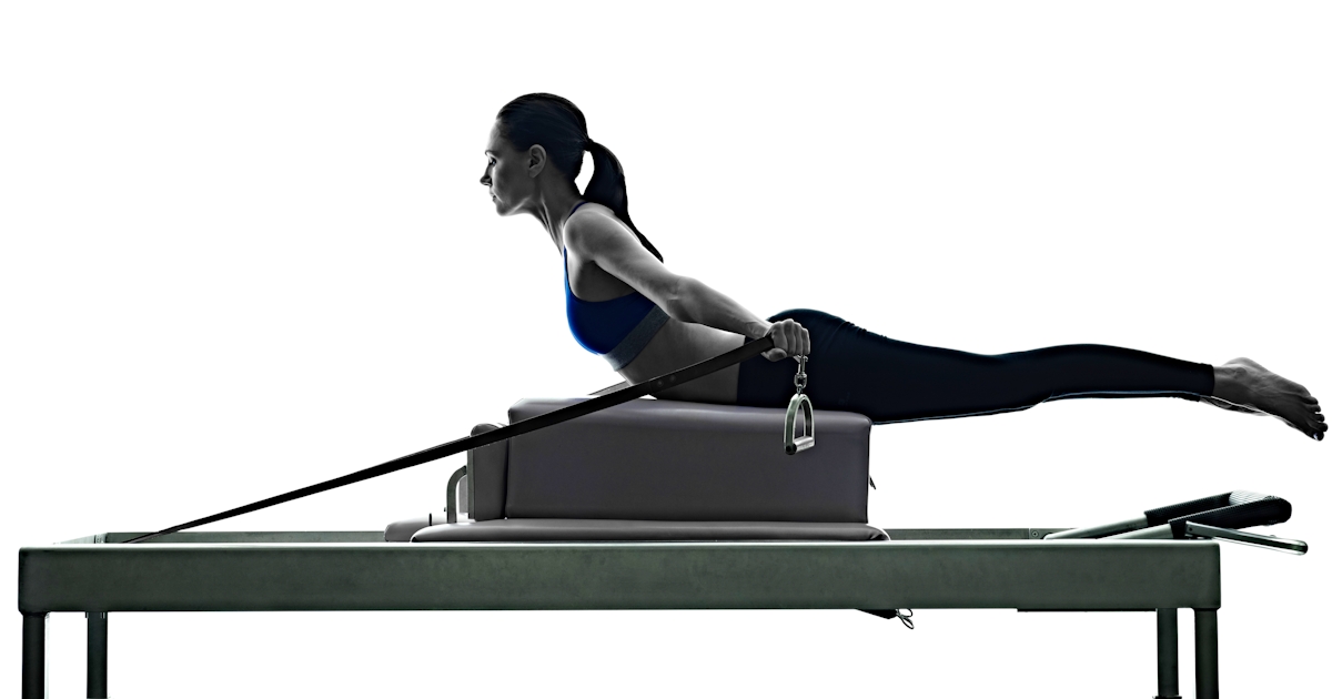 The image shows a person performing an exercise on a Pilates reformer, extending their body while using resistance straps.