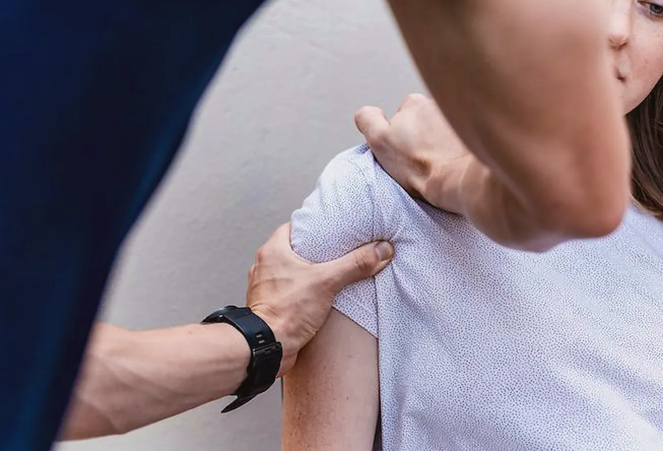 Practitioner assessing a patient's shoulder and neck for thoracic outlet syndrome and arm tingling