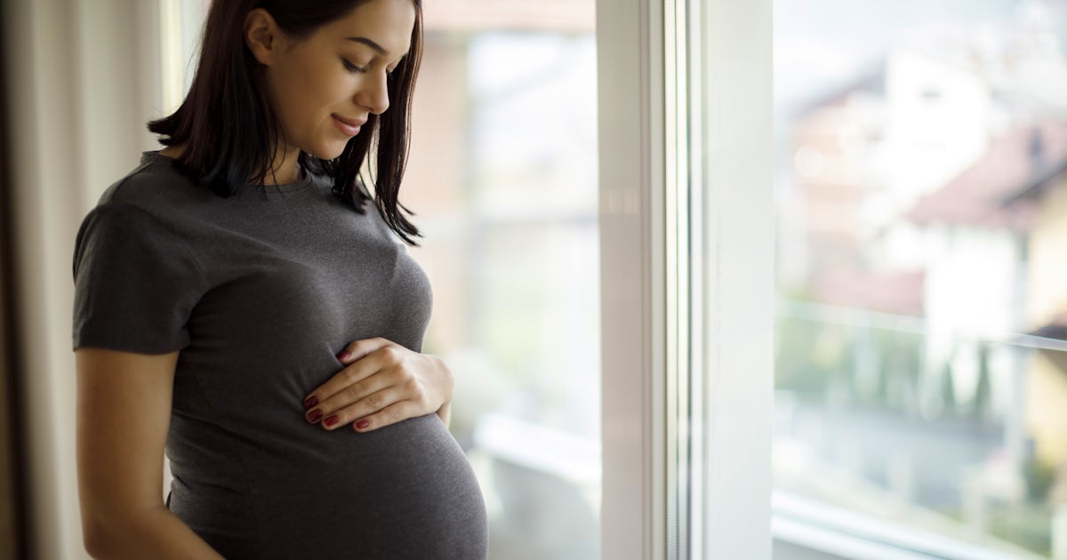 Portrait of young happy pregnant woman standing by