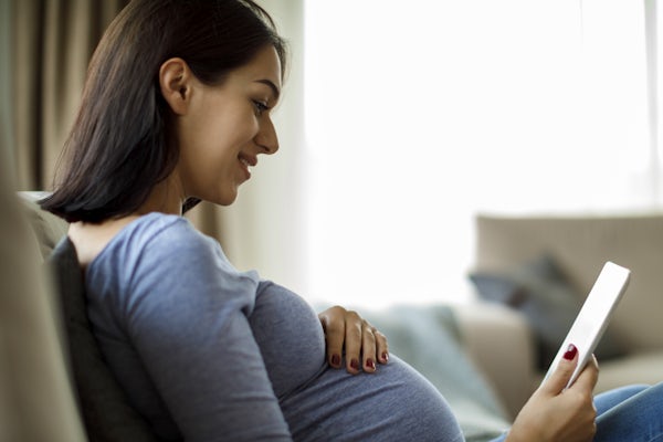 Pregnant woman using digital tablet at home