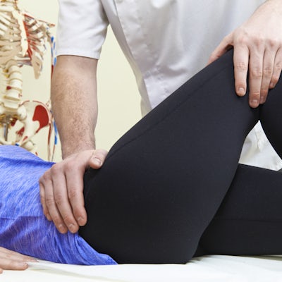 Male Osteopath Treating Female Patient With Hip Pr
