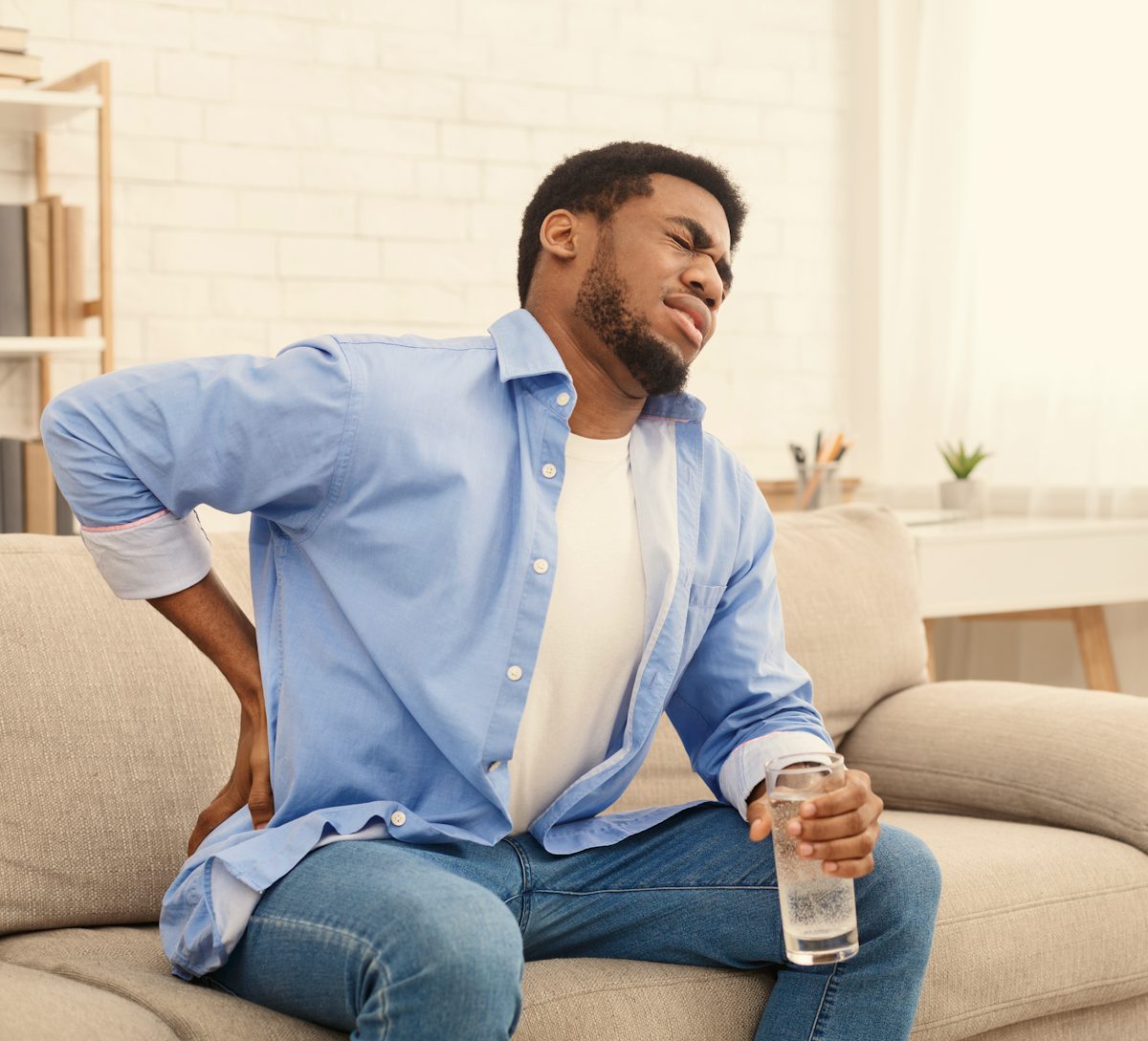 Young black man with back pain at home