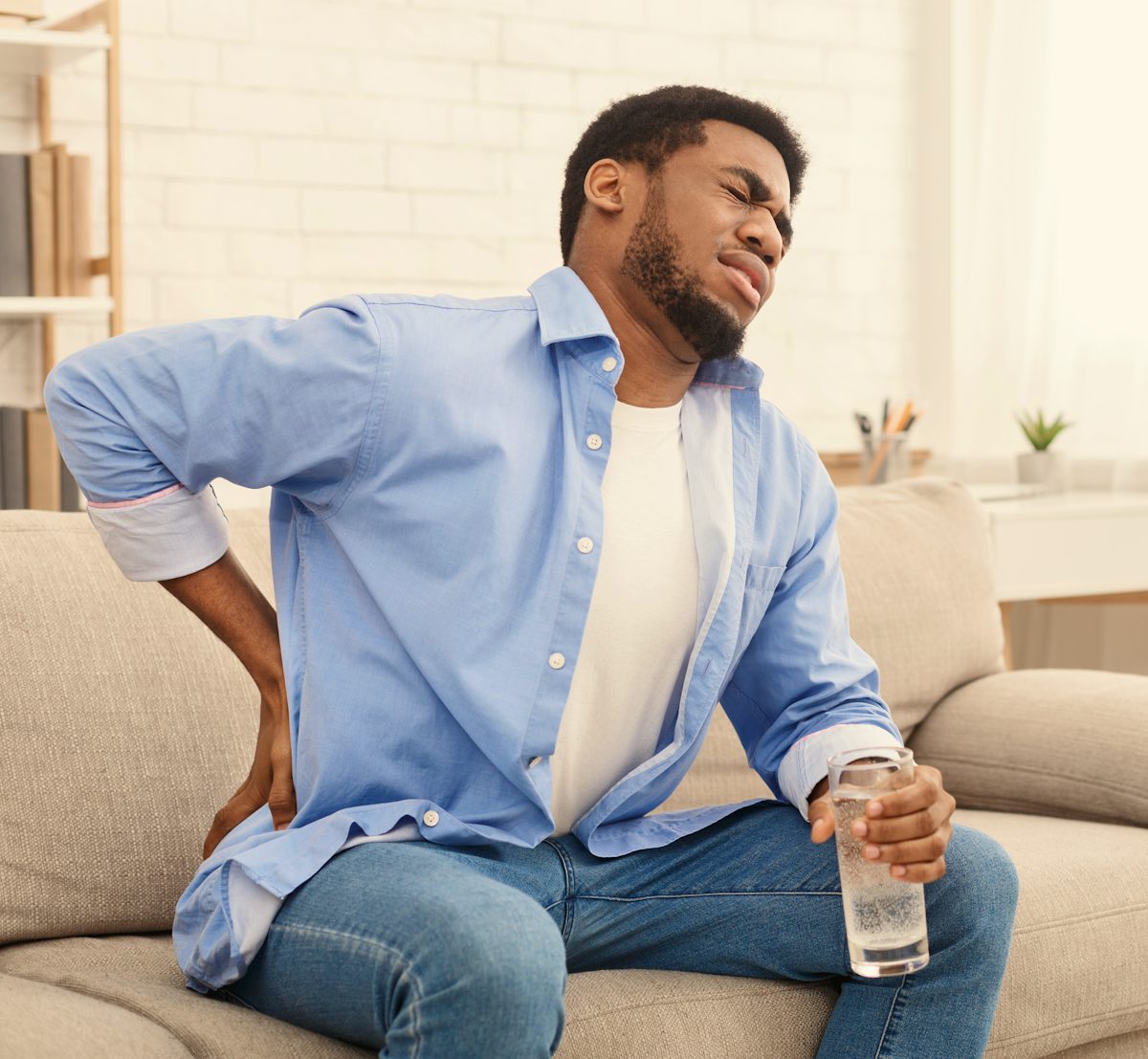 Young black man with back pain at home