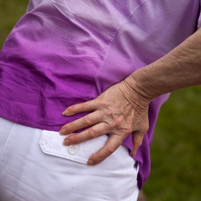 Senior woman holding hip and bending over