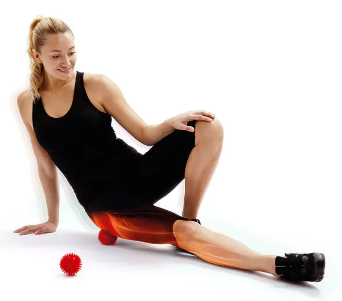 Person using a red spikey massage ball under the thigh