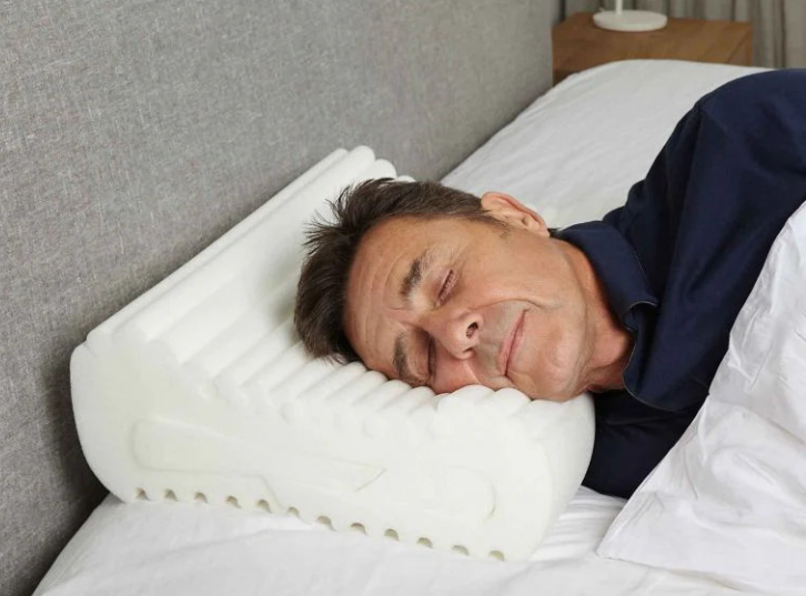 Man side sleeping on a contoured cervical support pillow