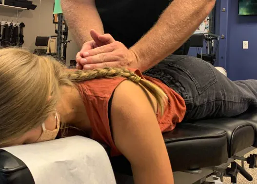 Chiropractor providing manual treatment to a patient with scoliosis-related back stiffness and discomfort