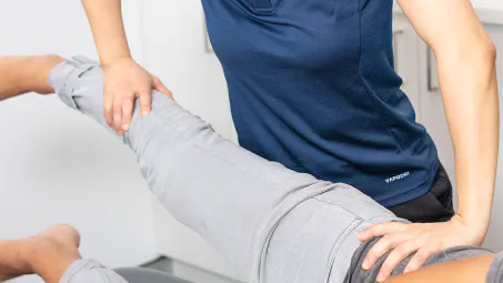 Practitioner assessing and moving a patient's hip during rehabilitation for lateral hip pain