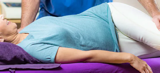 Practitioner assessing and moving a patient's hip during treatment for hip osteoarthritis
