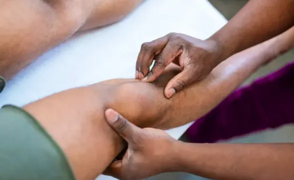Practitioner assessing a patient's knee during conservative treatment for knee osteoarthritis