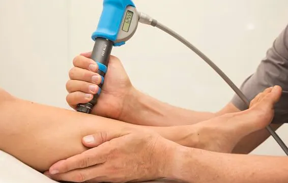 Clinician applying a handheld therapy device to the lower leg