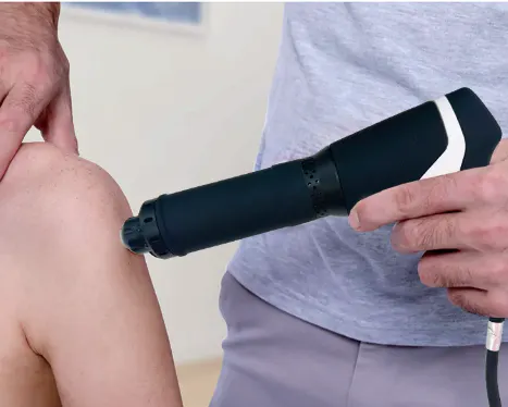 Shockwave therapy applicator being used on a patient's knee