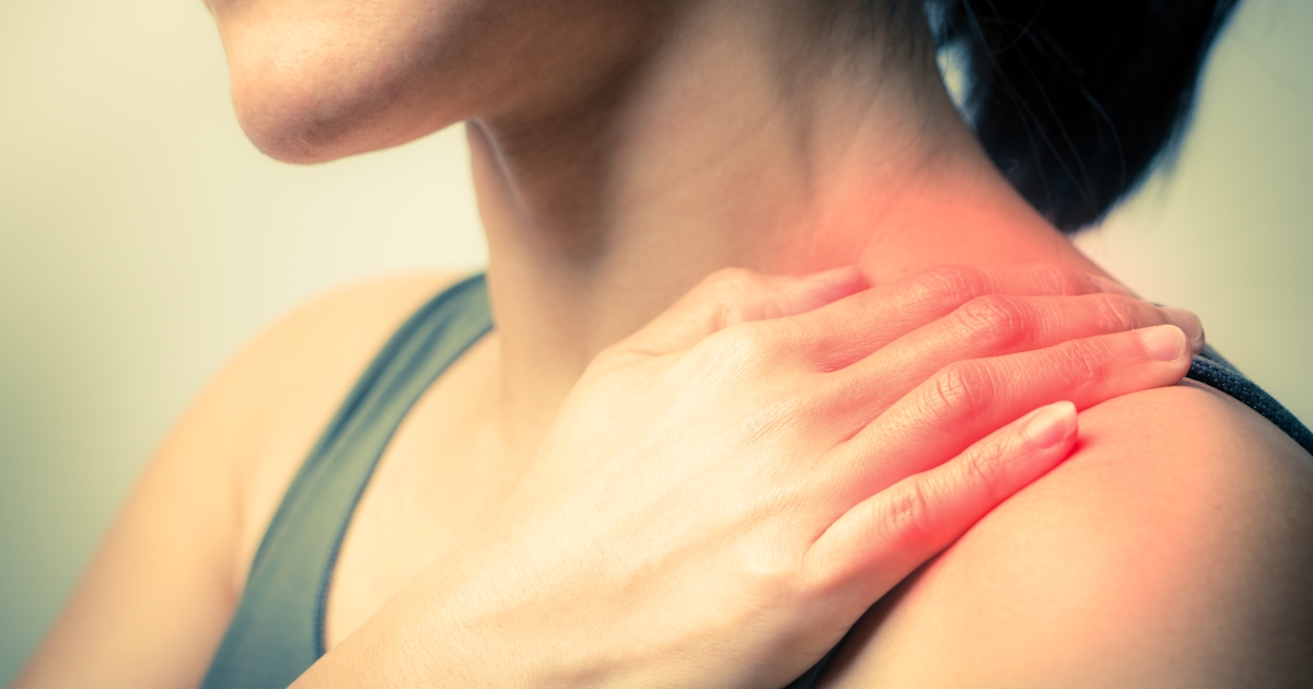 The image shows a person gently holding their shoulder, indicating discomfort or pain in that area.