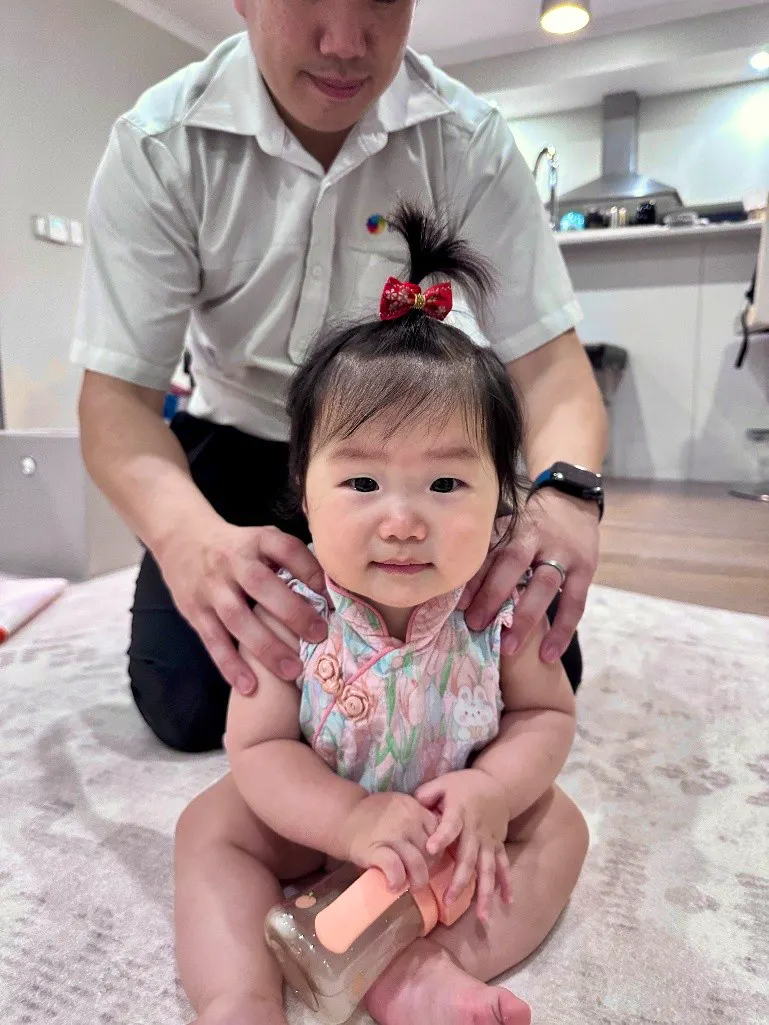 Smiling baby girl sitting upright during a paediatric chiropractic check-up