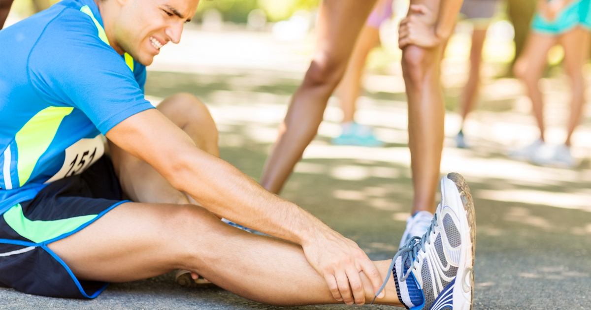 Man Suffering From Ankle Pain On Street During Mar