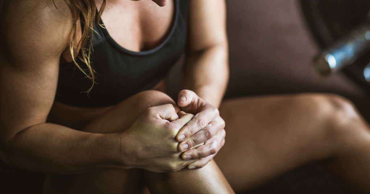 female athlete with knee pain while weight lifting