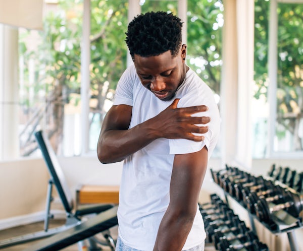 Sportsman holding painful shoulder in gym