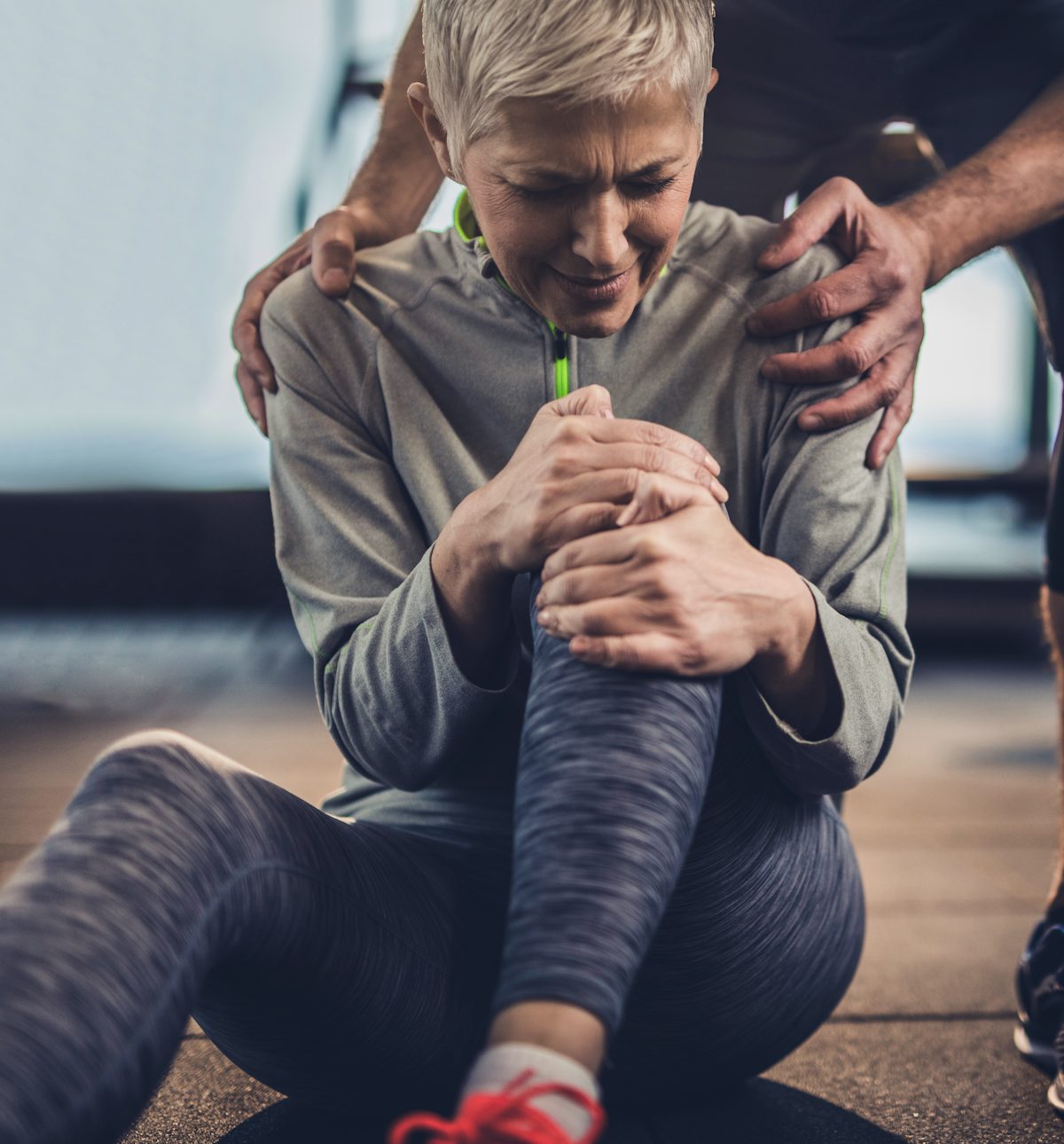 Senior female suffering with knee pain while exercising