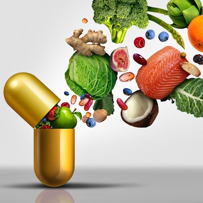 gold vitamin capsule supplement with colorful veggies spilling out