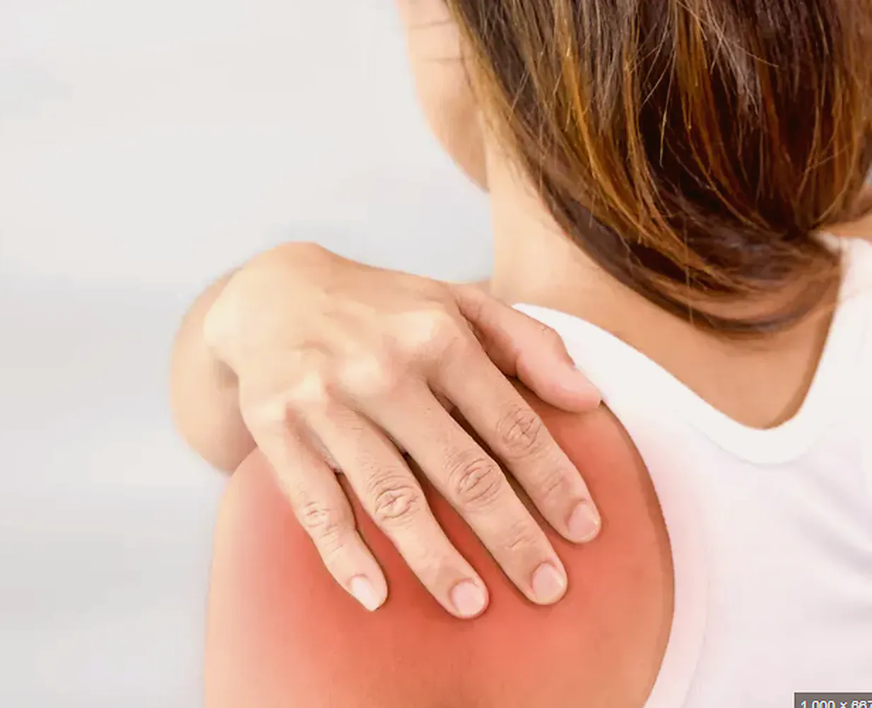 Woman holding her shoulder with frozen shoulder pain, stiffness, and restricted movement