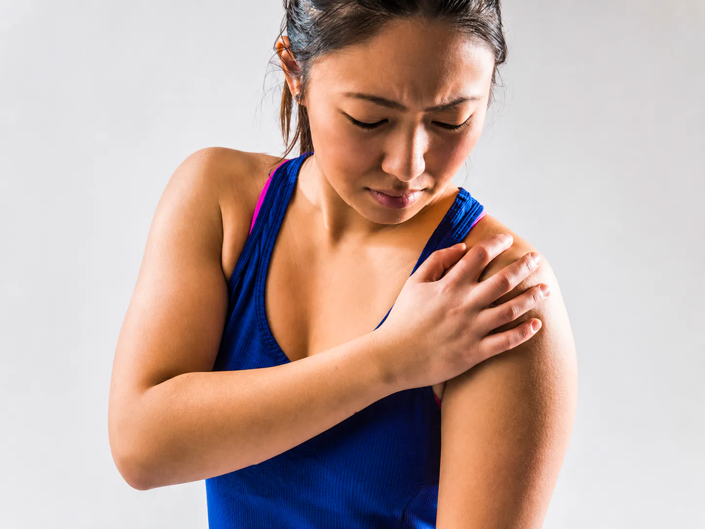 Woman holding her shoulder with subacromial bursitis pain, inflammation, and restricted movement