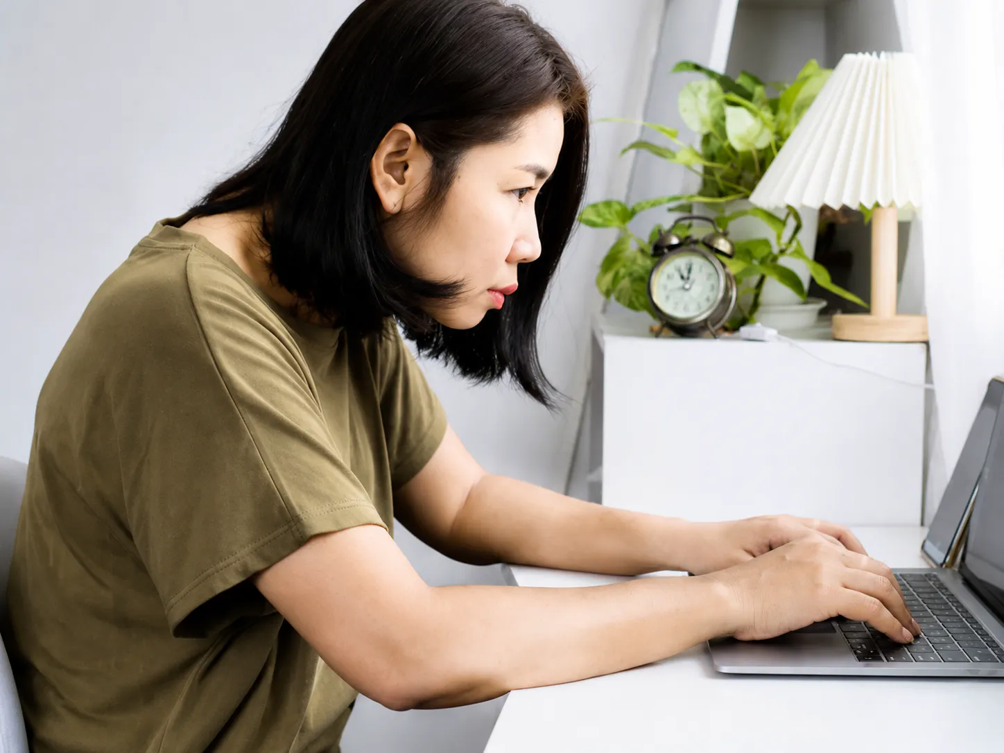 Woman using a laptop with forward head posture and neck strain from prolonged computer use