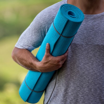 Close-up on a man doing holding a yoga mat outdoor