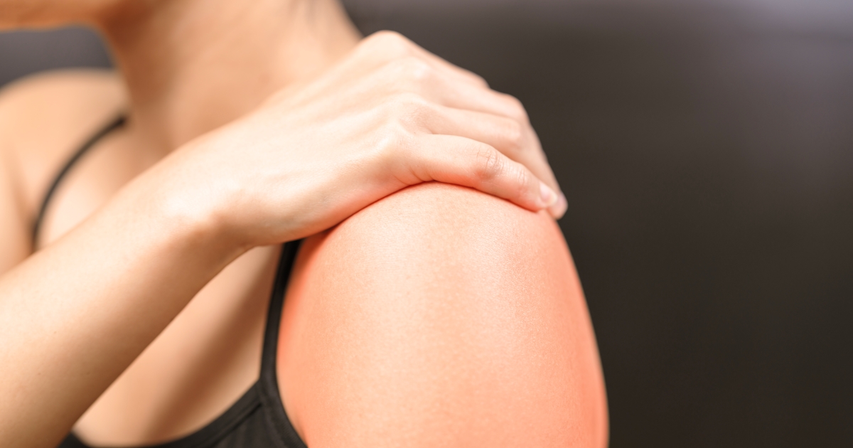 up close of womans left shoulder with right hand on top of left shoulder black tank top