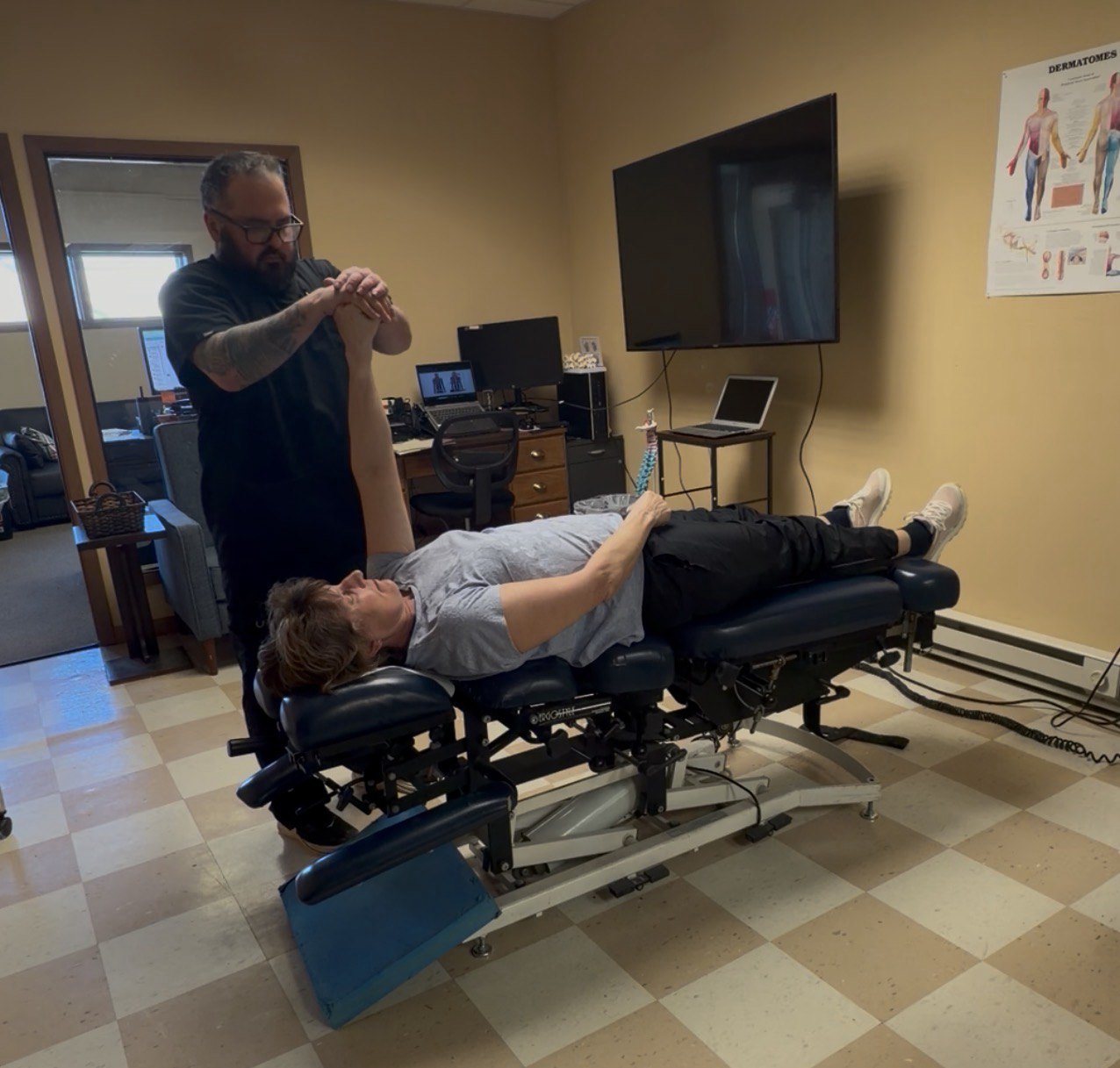 Patient receiving shoulder and arm movement care on a chiropractic treatment table
