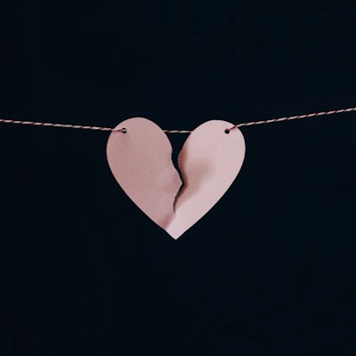 A paper heart on a string is nearly torn down the middle
