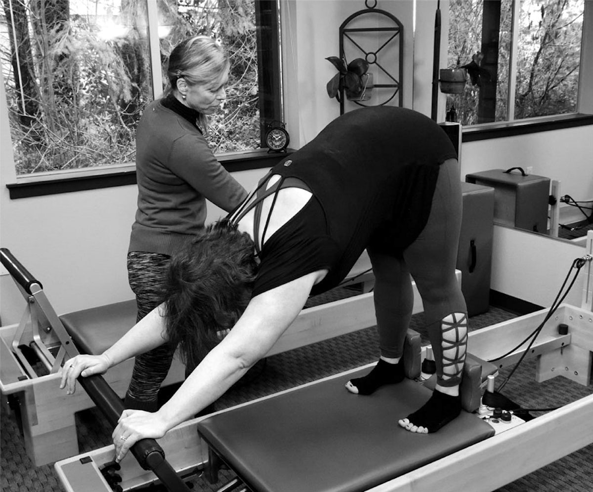 instructor teaching woman how to use pilates reformer