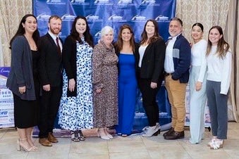 award winning woman in a group photo with 8 other people