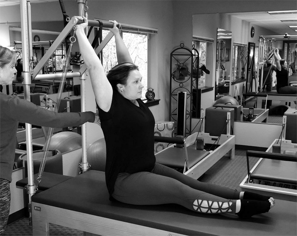 woman doing pilates with instructor