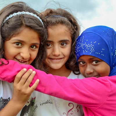 Three girls of multiple ethnicities smiling and hugging