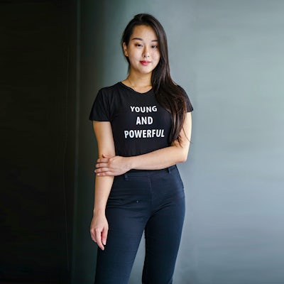 A young woman wears a shirt that says YOUNG AND POWERFUL