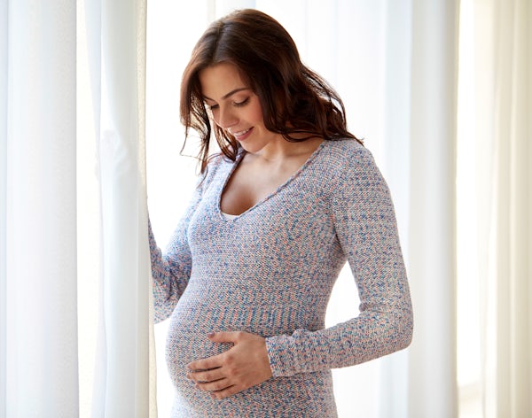 pregnant person smiles while looking at belly