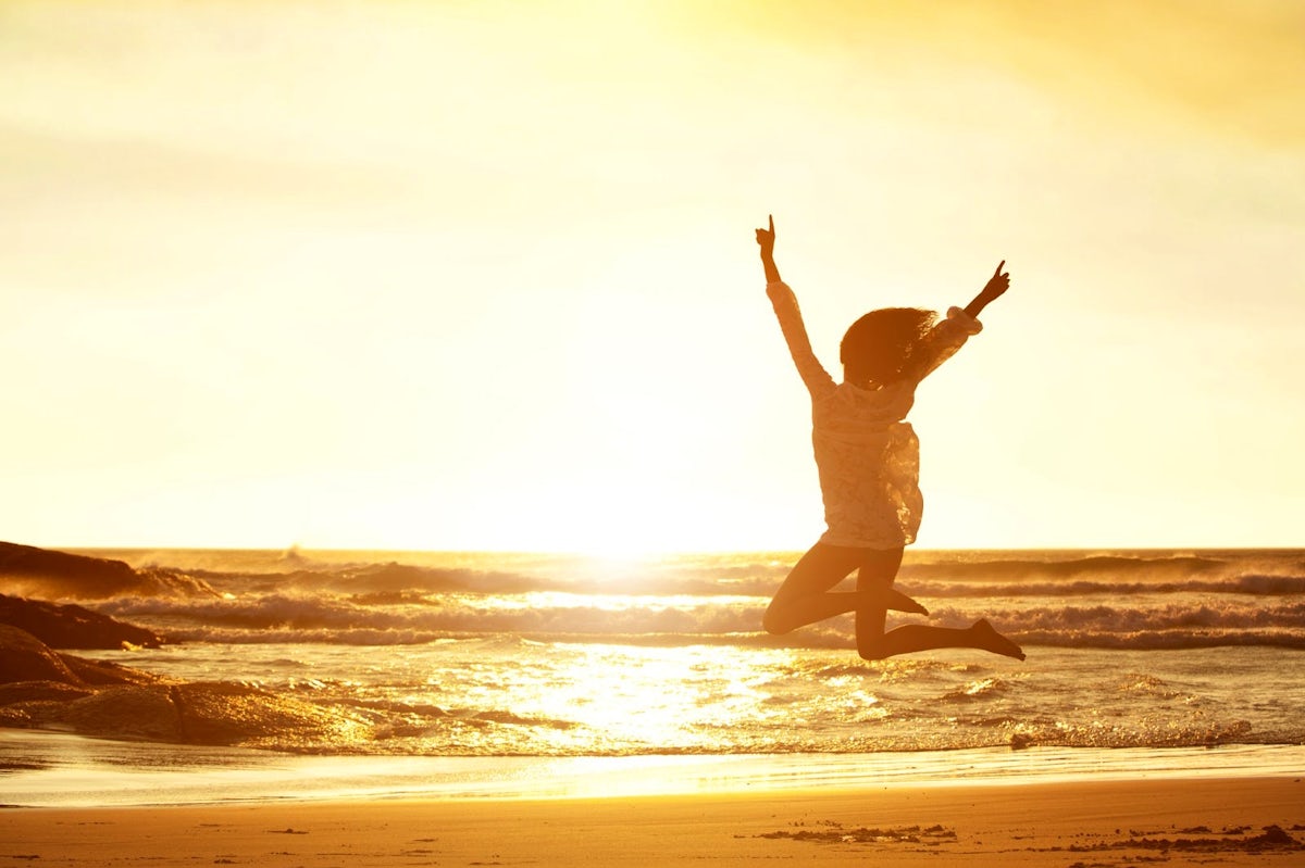 woman jumping for joy on a beach